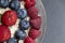 Set of summer berries with oatmeal and chia seeds in a small glass bowl on a black stone background. Perfectly healthy summer