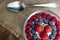 Set of summer berries with oatmeal in a small glass bowl on a napkin and wooden background. Perfectly healthy summer breakfast.