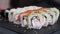 Set of Sushi Rolls with tuna, salmon, cucumber, avocado on rotating table on black Background close-up.