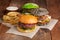 Set of three mini homemade Burger, Idaho potatoes with sauce and vegetables on a old wooden background. the concept of junk food a