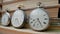 Set of three silver antique pocket watch with against background of stacks of books. Retro clock near old textbooks with