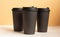 Set of three takeaway black coffe cup on neutral background. Mock -up, nobody, front view.