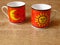 A set of two fine porcelain ware tea coffee cups in red, black and yellow on oak wood rustic background.