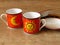 A set of two fine porcelain ware tea coffee cups in red, black and yellow and two saucers on oak wood rustic background.