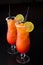 Set of two summer refreshing coctails isolated on a black background. Orange alcoolic coctail or a lemonade