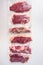 Set  of  vacuum packed organic raw beef alternative cuts: top blade, rump, picanha, chuck roll steaks, over white background, top