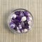 Set of various amethyst natural mineral stones and gemstones on glass plate and grey background
