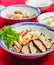 Set of Vietnamese Noodles with Pork and Shrimp Recipe soup bowl on the red carpet with sauce and green lemon.