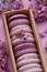 Set of violet and lilac macarons in cardboard gift box with lilac flowers