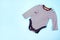 Set of warm baby clothes with bodysuits for boy on blue background. Collection of cute baby clothes. Gift for the birth of a boy