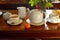 A set of white hot tea pot , teapot, tea cups on mug, milk jar on wooden table and an orange fruit wooden table in afternoon. Trad