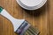 A set of white paint brushes, a metal can with white paint on a wooden texture table