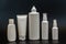 Set of white plastic bottles packages, tubes on black background. For cosmetic product. For cream, bottle with spray, lotio