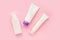 Set of white tubes of face skin care cream isolated on pink background  top view  mockup