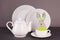 Set of white utensils for lunch and tea party and funny easter bunny on a gray background. Easter set for table service