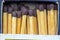 set of wooden matchsticks with brown colored explosive together and lined up.