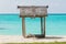 Set of wooden stools and tables for visitors placed under coconut palm trees on the white sands of the beach facing Malet island.