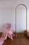 Setting of pink chair with pink bed runner laying on with gold partition rod and white painted wall backgroung