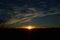 Setting sun in the dark sky over the field with the transmission towers