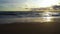 The setting sun illuminates the sandy shore