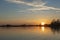 The setting sun illuminates a single contrail over the lake Zoetermeerse Plans in Zoetermeer, Netherlands