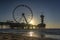 The setting sun is just above the Pier in Scheveningen and glistens in the wet sand on the water line of the North Sea