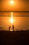 the setting sun sets over the horizon and is reflected on the surface of a salt lake. people walk and collect salt.