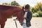 Setting up equipment for the ride. Young man with a horse is outdoors