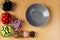 Seven bowls with tomatoes, black olives, cucumbers, colored peppers, pink salt, onion and walnuts