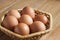 Seven brown chicken eggs lay in a wicker basket on a table.