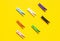 Seven colored clothespins in a row on a yellow background