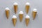 Seven cornets with vanilla ice cream on grey