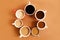 Seven cups of coffee on brown background, top view