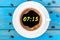 Seven fifteen hours or 7:15 on morning cup of coffee like a round clock face. Top view on blue wooden background