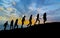 Seven friends walk on mountain path in sunset