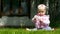 Seven month baby plays on a lawn with a flower