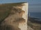 Seven Sisters - white cliffs, a lighthouse and blue seas on a bright, sunny day.