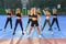 Seven slender sporty young women doing body tilts to left and right sides at the outdoors workout in urban park.