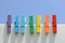 Seven wooden multi-colored clothespins, painted in the colors of the rainbow, against the blue sky