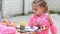 Seven-year girl choose the right color ink drawing in an album, sitting at table with another girl