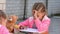 Seven-year girl funny erases eraser, doing drawing with his sister in street