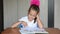 Seven-year girl schoolgirl doing homework sitting at table