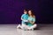 A seven-year-old boy and a smiling thirty-year-old woman open a gift box together while sitting on the floor