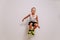 Seven-year-old Caucasian boy in basketball uniform jumping high on white background