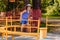 A seven-year-old cheerful boy in a striped t-shirt and hat rides a yellow children`s carousel in the summer