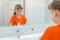 Seven-year-old girl washing her face looks at herself