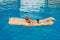 Seven-year-old tanned child swims on an inflatable mattress in the outdoor pool