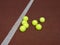 Seven Yellow tennis balls on brown court