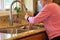 Seventy year old woman washes hands in sink