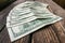 Several 100 dollar banknotes in semicircle layout on the aged rough wooden windowsill.